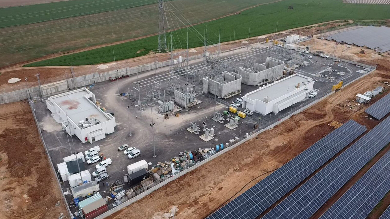 Aerial view of a high-voltage substation next to a solar field